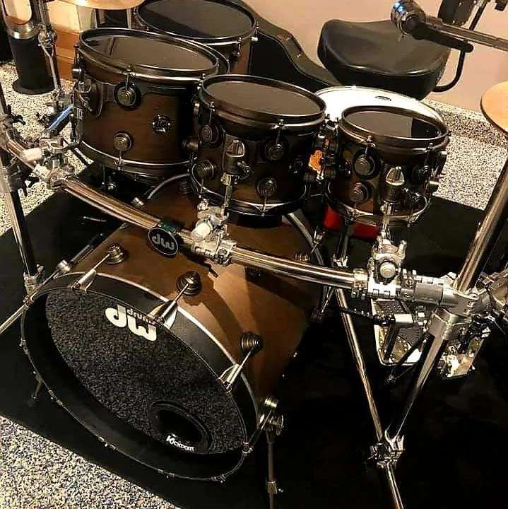 DW Drums drum kit with dark brown finish, multiple toms, kick drum with Kickport, and chrome hardware in a studio.